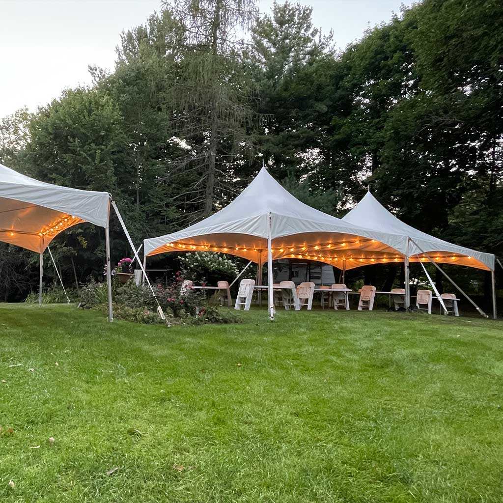 Multiple connected high peak tents with string lights at dusk for wedding reception in Tampa Bay