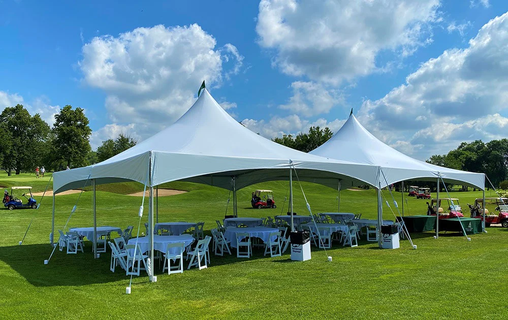 Twin high peak tents on golf course with round tables and chairs for corporate event