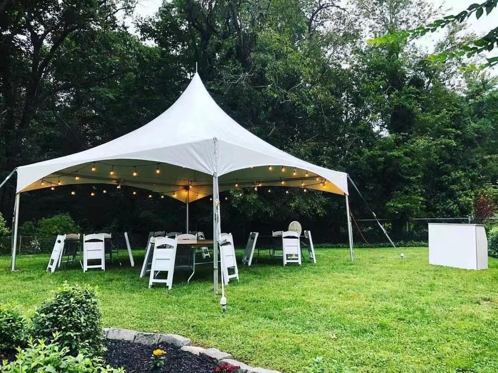 High peak tent with string lights and white folding chairs on lawn in Lithia FL